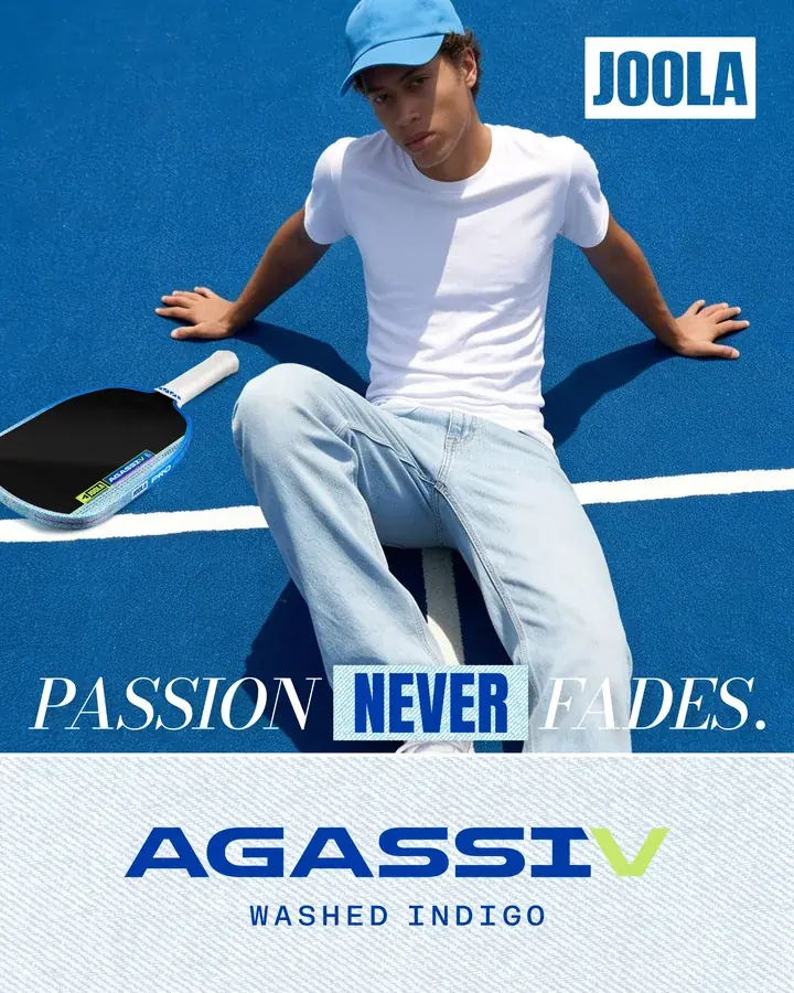 Người chơi mặc quần bò ngồi trên sân pickleball xanh, cây vợt Washed Indigo đặt bên cạnh